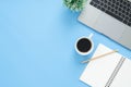 Top view office desk with laptop, notebooks and coffee cup on blue color background. Royalty Free Stock Photo