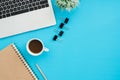 Top view office desk with laptop, notebooks and coffee cup on blue color background. Royalty Free Stock Photo