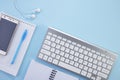 Top view office desk with notepad, keyboard, paper notepad, and supplies on blue background