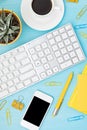 Top view of office desk. Table with keyboard, smartphone, clipboard and office supplies. Flat lay home office workspace, remote