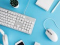 Top view of office desk table with notebook, plastic plant, smartphone and keyboard on blue table background, graphic designer, Cr Royalty Free Stock Photo