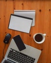 Top view of an office mock up with a laptop, blank mobile phone, cup of coffee and blank notebooks