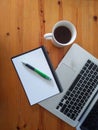 Top view of an office mock up with a laptop, blank notebook, a cup of coffee and a pen