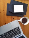 Top view of an office mock up with a laptop, blank tablet on top of stacked notebook, and a cup of coffee