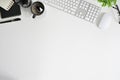 Top view office table desk. Workspace with blank computer keyboard and office supplies, green leaf, and coffee cup on white Top Royalty Free Stock Photo