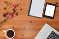 Top view of an office table mock up with a laptop, blank notebook, tablet, a cup of coffee and flowers with copy space at the cen