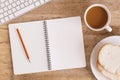 Top view of the office table On the table there are notebook, coffee cup, bread, pencil and keyboard