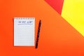 Top view of office tools with blank notebook and pen on orange, yellow and red background. Space for text Royalty Free Stock Photo