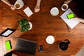 Top view on office wooden table and black tablet phone with green screen and people hands. Office stuff nearby. Chroma key.