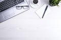 Top view of office work space, wooden desk table with laptop notebook,keyboard ,pen,eyeglasses,phone,notebook and cup of coffee. Royalty Free Stock Photo