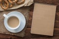 Top view office workplace: ÃÂ¡ardboard notepad with bagels and coffee on wooden table