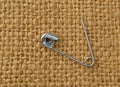 Old safety pin on burlap cloth Royalty Free Stock Photo