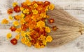 Top view on old styled broom sweeping yellow, orange amd red flowers on wooden background. Marigolds