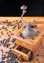 Top view of old wooden coffee grinder with ground coffee in drawer, and coffee beans on wooden table, black background Royalty Free Stock Photo