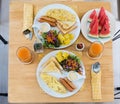 Top view of omelet with orange juice, watermelon, croissants, cereals and fruits on wooden table. Royalty Free Stock Photo