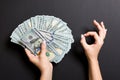 Top view of one hundred dollar bills in one hand and showing okay gesture with another hand on colorful background. Prosperity and Royalty Free Stock Photo