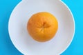 Top view of one orange grapefruit on white plate on blue background. Diet concept Royalty Free Stock Photo