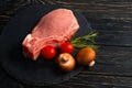 Top view of one pieces raw pork chop steaks with cherry tomatoes Champignon mushrooms on a black stone cutting board Royalty Free Stock Photo