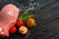 Top view of one pieces raw pork chop steaks with cherry tomatoes Champignon mushrooms on a black stone cutting board Royalty Free Stock Photo