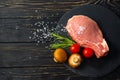 Top view of one pieces raw pork chop steaks with cherry tomatoes Champignon mushrooms on a black stone cutting board Royalty Free Stock Photo
