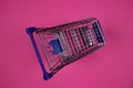 Top view on one single isolated shopping cart, purple magenta background Royalty Free Stock Photo