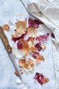 Top view of onion peelings with a knife and a kitchen towel on a white surface