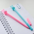 Top view of an open blank notebook with a blue and pink rabbit pen and funny kawaii clips Royalty Free Stock Photo
