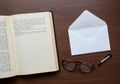 Vintage Open Book with Eyeglasses Envelope and Pen on Wooden Table Royalty Free Stock Photo