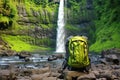 top view of open camping backpack by waterfall