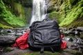 top view of open camping backpack by waterfall