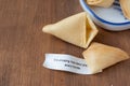 Top view of open fortune cookie with message, on wooden table, horizontal,