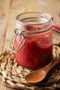 Top view of open glass jar with homemade tomato and beetroot ketchup, on wood and wooden spoon,