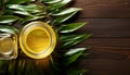 Top view of open jars of oil with bamboo leaves on a wooden surface