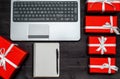 Top view of open laptop computer, blank notebook and red gift boxes on wood table, copy space. Flat lay. Online shopping, holidays Royalty Free Stock Photo