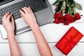 Top view of open laptop computer, bouquet of roses, gift box and woman hands typing on keyboard. Valentines day, Womans day Royalty Free Stock Photo