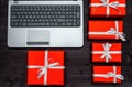 Top view of open laptop computer and red gift boxes on wooden table, copy space. Flat lay. Online shopping, winter holidays sales. Royalty Free Stock Photo