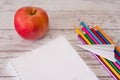 Top view of the open note pad with copyspace and colorful pencils with paper airplane and red apple on a wooden desk. Concept of Royalty Free Stock Photo