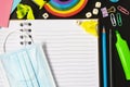 Top view of open notebook with face mask, colorful pencils, rainbow eraser, notebook, sticky notes. Flat lay. Royalty Free Stock Photo