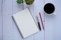 Top view of open school notebook with blank pages, red pencil, and pen with a coffee cup on white table background. Royalty Free Stock Photo