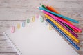 Top view of open sketchbook with blank page copyspace and colorful pencils and paper clips on a wooden desk. Mock up Royalty Free Stock Photo