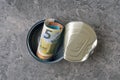 Top view of open tin can with a roll of Euro banknotes