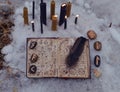 Top view of open witch book with spells, burning candles and runes outside in winter