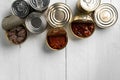 Top view of opened cans with fish conserves on wooden background