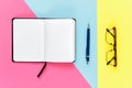 Notebook, pencil and glasses on multi colored background Royalty Free Stock Photo