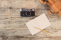 Top view on opened notebook, old, vinage camera and suitcase on wooden office desk, old planks. Hipster style