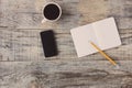 Top view on opened notebook, smartphone, highlighters, and other equipment on wooden office desk, old plancs. Hipster style