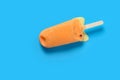 orange color chocolate outer popsicle with beans inside starts melting on blue background Royalty Free Stock Photo