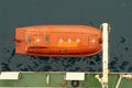 Top view on the orange colour life boat with reflective tape stickers secured with davits. Royalty Free Stock Photo