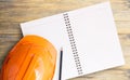 Top view with orange safety engineer helmet and notebook on wood