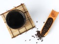 Top view of organic fetid cassia seed also called ketsumei-shi on wooden spoon isolated on a white background.